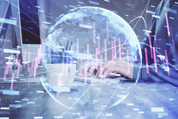 Multi exposure of graph with man typing on computer in office on background. Concept of hard work.