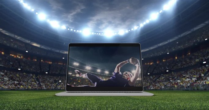 A laptop with a football moment on a screen is opening on the field of the professional football stadium. Stadium is made in 3d with animated crowd.