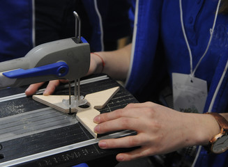 Girl cuts a star from a piece of plywood with an electric saw