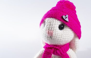 Cute handmade white rabbit in a pink hat wishes you a happy Easter! White background, frame for text, close up
