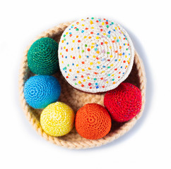 Happy Easter, close-up of a handmade knitted cake in a basket with yellow, orange, red, blue and green Easter chicken eggs isolated on a white background, top view