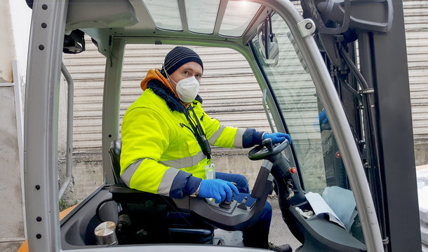 coronavirus : man with protective mask and gloves drives the forklift