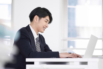 笑顔でノートパソコンで作業をする日本人男性ビジネスマン