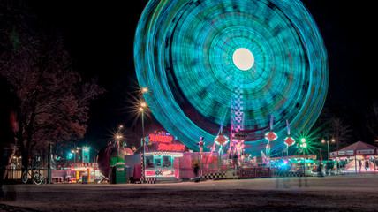 long exposure photograph of ferris wheel with aquamarine lights at night parties