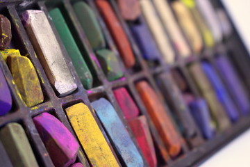 A close up photograph of an artist's box of used chalk pastels.  Art supplies, creative.