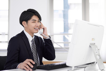 笑顔で電話の応対をする日本人男性ビジネスマン