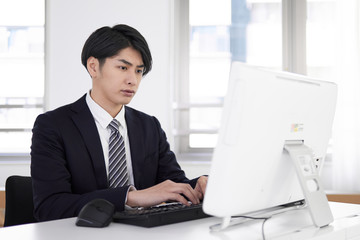 真剣な表情でパソコン作業をする日本人男性ビジネスマン
