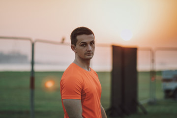 Fototapeta premium Young Adult Handsome Fitness Trainer Athlete Portrait Look Forward with Sunset Blurred Background