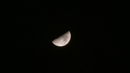 Close up of half moon with black sky background at night.