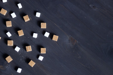 cane brown  and white sugar cubes on black wooden background