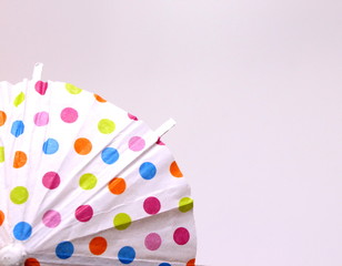 A close up photograph of a colorful cocktail umbrella isolated against a white background.  Fun party concept.