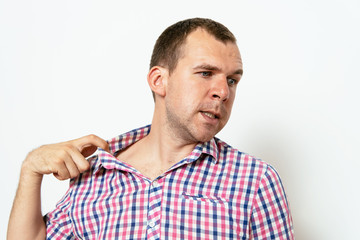 Closeup portrait of young man opening shirt to vent,it's hot. Negative emotion, facial expression, feeling