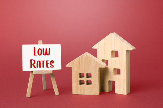 Figurines of houses and an low rates easel. Big promotions and discounts on home sales. Low demand for real estate and housing, economic downturn and recession. . Special purchase offers