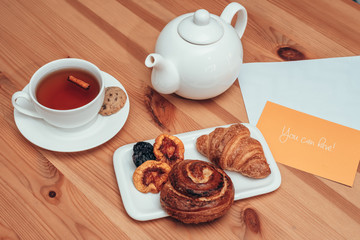 Aromatic tea with pastries and kettle on the table