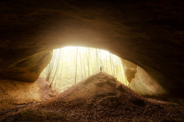 huge cave entrance with man silhouette in sunset light