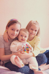 three little sisters on   bed at home.