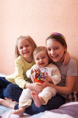 Fototapeta premium three little sisters on bed at home.
