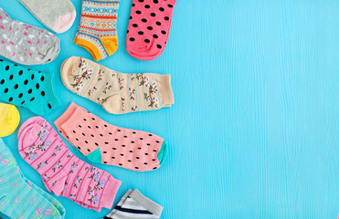 Socks for the cold seasons. A lot of different socks on a blue background. Clothing for autumn and winter and space for text. Colorful multi-colored socks.