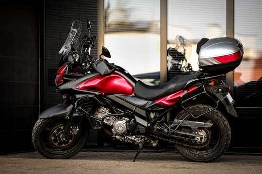 Motorcycle parked in front of office building. Beautiful shiny black motorbike with red details and storage trunk or top box behind the seat. Full length outdoor shot
