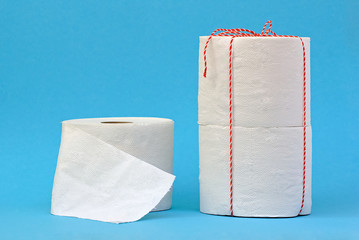 Toilet paper on light blue background. Toilet paper crisis because of Corona. Bottleneck. Toilet paper packed as a gift.