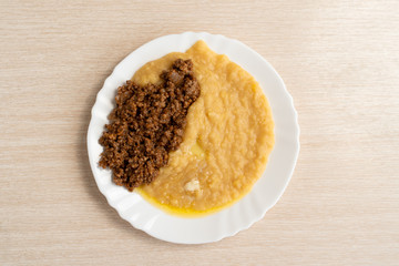 Yellow pea puree with meat in a white plate