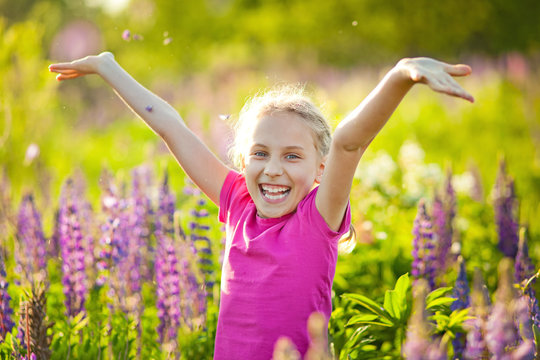 Portrait of a smiling child in a blooming lupine field at sunset. A Sunny evening in late spring. Lupin flowers like a source for honey. Children have allergies during the flowering period.