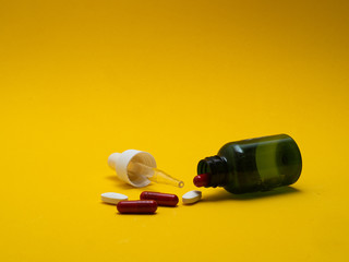 DROPPER WITH COLORED PILLS ON YELLOW