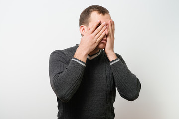  man covers his face by hand