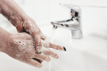 close-up shot of woman thoroughtly washing her hands with soap at lavatory, hygiene measure during...