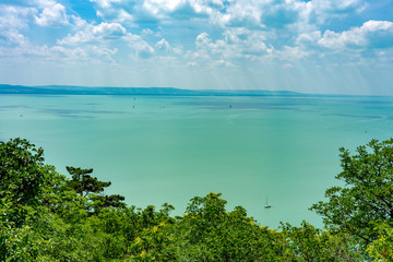 Hiking on a hill next to the Lake Balaton sunbeams over the sail boats