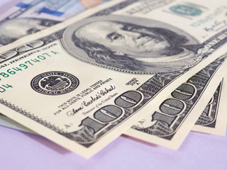 US money banknotes of 100 dollars old and new type lie on a light purple paper background close-up. Interest rate. Emission. National currency. Focus on the Fed stamp. Macro