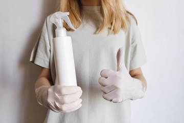 Woman in medical gloves holds a disinfectant spray. Protecting body from viruses and bacteria. Hand hygiene, sterile uniform. The fight against epidemic. Safety for your life. Prevention and control