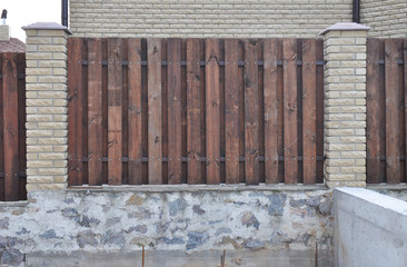 A wooden fence design with brick support pillars and brick foundation.