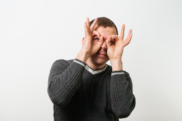 man looking through hands, making binoculars