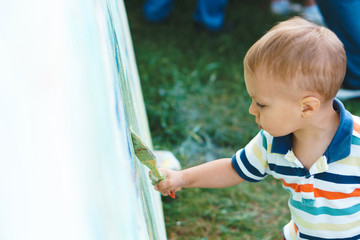 boy holding brush painting at park