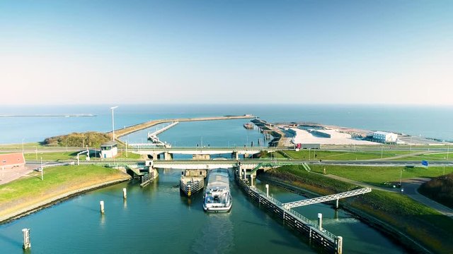 Enclosure Dam (Afsluitdijk): Large Cargo Ship Going Under the Bridge with Traffic to Cross the Dam, Rising Shot Looking Down - Friesland, Netherlands / Holland &ndash; 4K Drone Footage