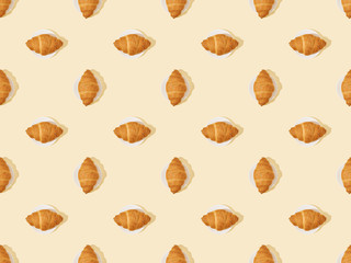 top view of fresh croissants on beige, seamless background pattern