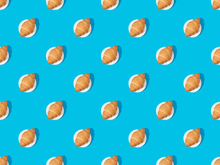 top view of fresh croissants on plates on blue, seamless background pattern