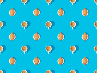 top view of croissants on plates and coffee on blue, seamless background pattern