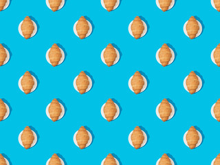 top view of fresh croissants on plates on blue, seamless background pattern