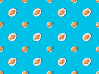top view of fresh croissants on plates on blue, seamless background pattern
