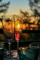 Glass of champagne or wine on table on terrace during evening. Sunset and trees in the background. Home comfort, relaxation, calm, tranquility.