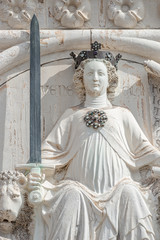 Ancient facade sculpture of a princess with sword and lions as the top decoration of Doge's Palace in Venice, Italy, summer time, closeup, details