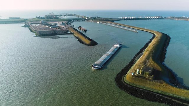 Enclosure Dam (Afsluitdijk): Large Cargo Ship with the Sluice it Came Through Behind It, Zooming Out Overview - Friesland, Netherlands / Holland &ndash; 4K Drone Footage