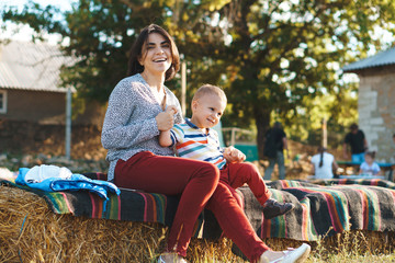 mother holding son's hands on haystack