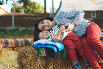 laughing mother and son laying on haystcak