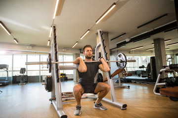 Obraz na płótnie Canvas Young sportsman lifting a barbell at the gym