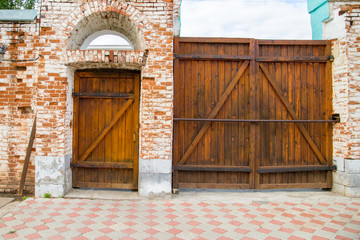 old red brick gate with wooden doors, paved walkway