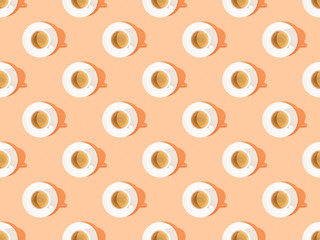 top view of cups of fresh coffee on plates on orange, seamless background pattern