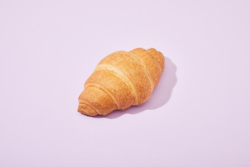 fresh tasty croissant on violet background
